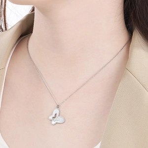 Detailed close-up of a silver butterfly necklace with white shell inlay on a female model