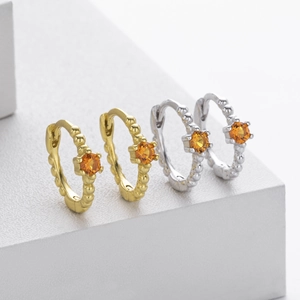 Detail of S925 silver hoop earrings with orange gemstones and beaded texture