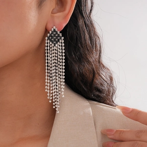 Macro shot of silver tassel earrings with black diamond rhombuses worn by a model