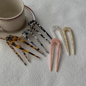 Lot d'épingles à cheveux en forme de U en acétate avec motifs marbre et léopard sur fond blanc
