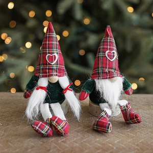Pair of Christmas long-legged gnomes with plaid hats in front of a warm festive tree