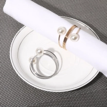 Dettaglio di portatovaglioli a renna in oro e argento con perle su piatto bianco