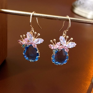 Détail macro de boucles d'oreilles pendantes en pierre bleue et fleurs en cristal