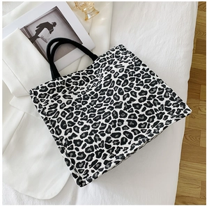 Close-up of leopard print tote bag texture and rope handles on stylish white blazer