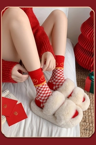 Festive red and white plaid cotton socks paired with plush slippers in a holiday setting