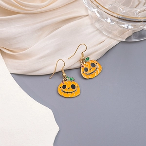 Macro detail of Halloween pumpkin drop earrings with orange enamel and gold-plated hooks