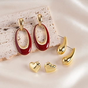 Detailed set of red oval drop earrings with golden waterdrop and heart studs on silk