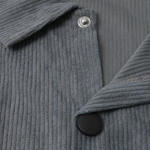 Macro shot of grey-blue corduroy shirt collar with black button and fine ribbed texture
