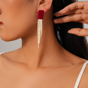 Détail macro de boucles d'oreilles carrées floquées bordeaux avec franges dorées en strass