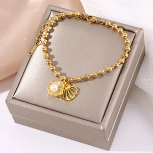 Elegant gold stainless steel beaded bracelet with shell charm and pearl on jewelry box