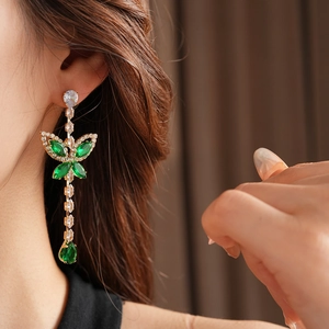Detailed close-up of zircon butterfly earrings with green water drop pendants on model