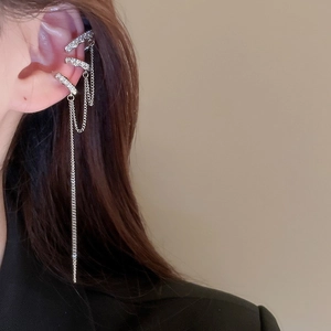 Gros plan sur un earcuff à pampilles argentées avec strass brillants porté sur l'oreille