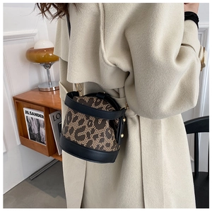 Chic leopard print bucket bag featuring black leather trim and metal D-ring hardware