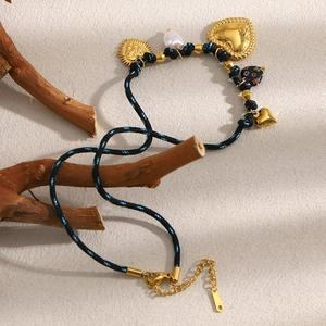 Detail of woven black rope necklace with 18K gold plated heart and sun charms and pearls