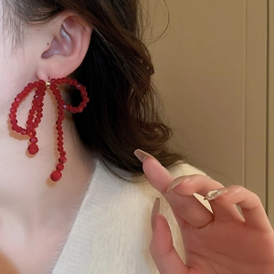 Gros plan d'une boucle d'oreille nœud en cristal rouge avec pompon sur un mannequin
