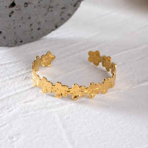 Minimalist gold stainless steel rib flower open bangle shown on textured white surface