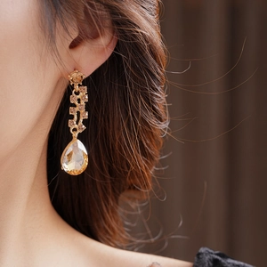 Close-up of golden teardrop earrings with champagne crystals on model's ear