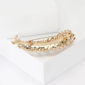 Detailed back view of gold feather brooch showing pin clasp and textured metal alloy