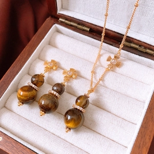 Macro shot of tiger eye stone gourd pendant necklace and earrings in a wooden jewelry box