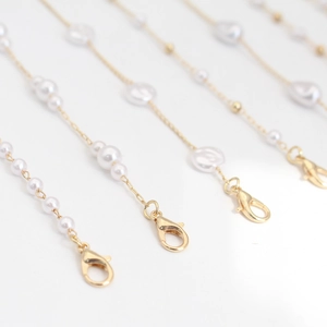 Elegant gold glasses chain with white pearls and lobster clasps on white background
