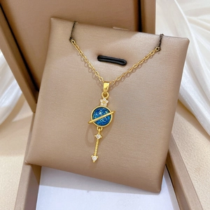 Detail of gold planet pendant with blue stone and star charms on beige silk