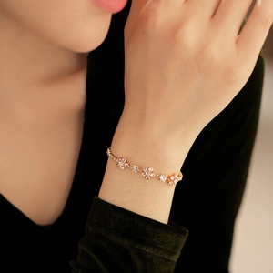Close-up of elegant gold chain bracelet with pink and white zircon floral charms