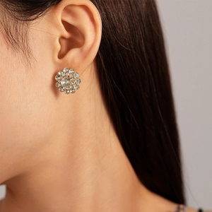 Close-up of a model wearing the crystal flower stud earrings in a gold finish