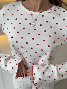 Close-up of white ribbed long-sleeve top with red heart print and ruffled cuffs
