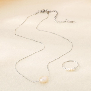 Detailed view of irregular freshwater pearl necklace and thin pearl ring on silk