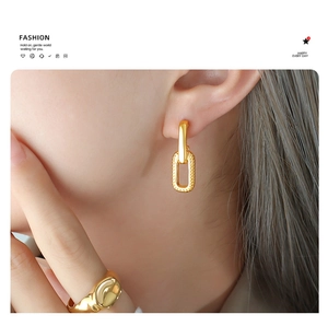Close-up of golden geometric U-shaped earrings and matching ring on a model