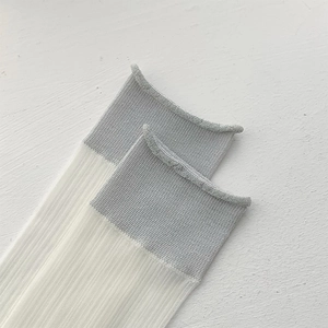 Detail of white ribbed socks featuring silver glitter metallic yarn and rolled cuffs