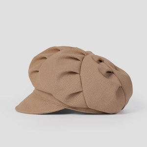 Gros plan sur la texture plissée et le tissage d'une casquette gavroche marron à visière
