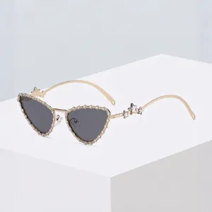 Heart-shaped rhinestone sunglasses with gold frames and star-detail on geometric display
