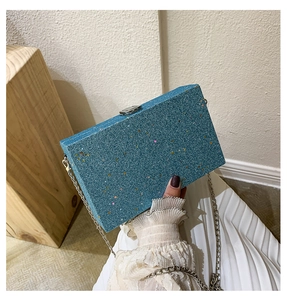 Close-up of blue sequined box clutch with silver chain and metallic buckle detail