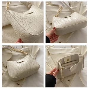 Dettagli della borsa sottobraccio beige con motivo a coccodrillo, catena bianca e tasca zip