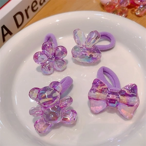 Detail of four purple crystal-textured hair ties featuring bear and floral charms