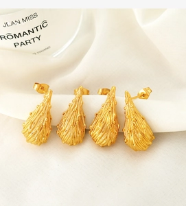 Detailed macro view of 18k gold plated long teardrop earrings with lava texture