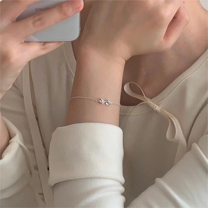 Close-up of a minimalist 925 silver bracelet with a bow pendant on a female wrist