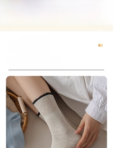 Close-up of contrast color cotton socks featuring delicate black wavy lace ruffled edges