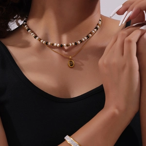 Double-layered tiger eye stone necklace with beaded choker and gold titanium chain on model
