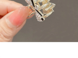 Detail of a small gold bow hair claw clip with sparkling clear rhinestones for girls