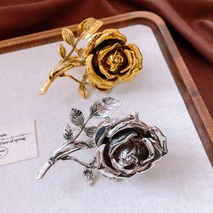 Detail of vintage carved rose rings in gold and silver on a wooden display tray