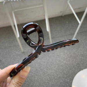 Detailed close-up of dark brown tortoiseshell claw clip with strong metal spring mechanism