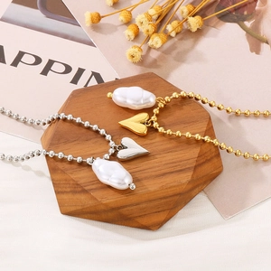 Detailed shot of gold and silver beaded necklaces with heart and baroque pearl charms