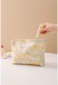 Détail de la broderie florale sur la trousse en lin avec insertion d'un soin cosmétique