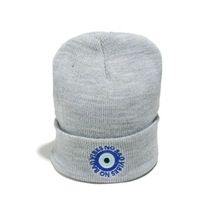 Detailed view of light grey knit beanie featuring blue evil eye and No Bad Vibes embroidery