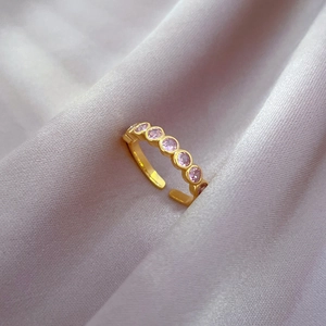 Detail of adjustable gold-plated ring with seven pink round-cut zircon stones