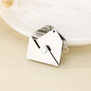 Detailed view of an openable silver envelope pendant with a card on beige fabric