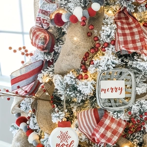 Dettaglio di nastro scozzese rosso e bianco con decorazioni merry e noel su albero innevato