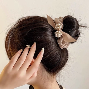 Chouchou élégant en satin champagne avec perles sur chignon, éclairage studio doux